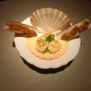 Saint jacques grillées à la plancha sur petits pois et couteaux rôtis en persillades.